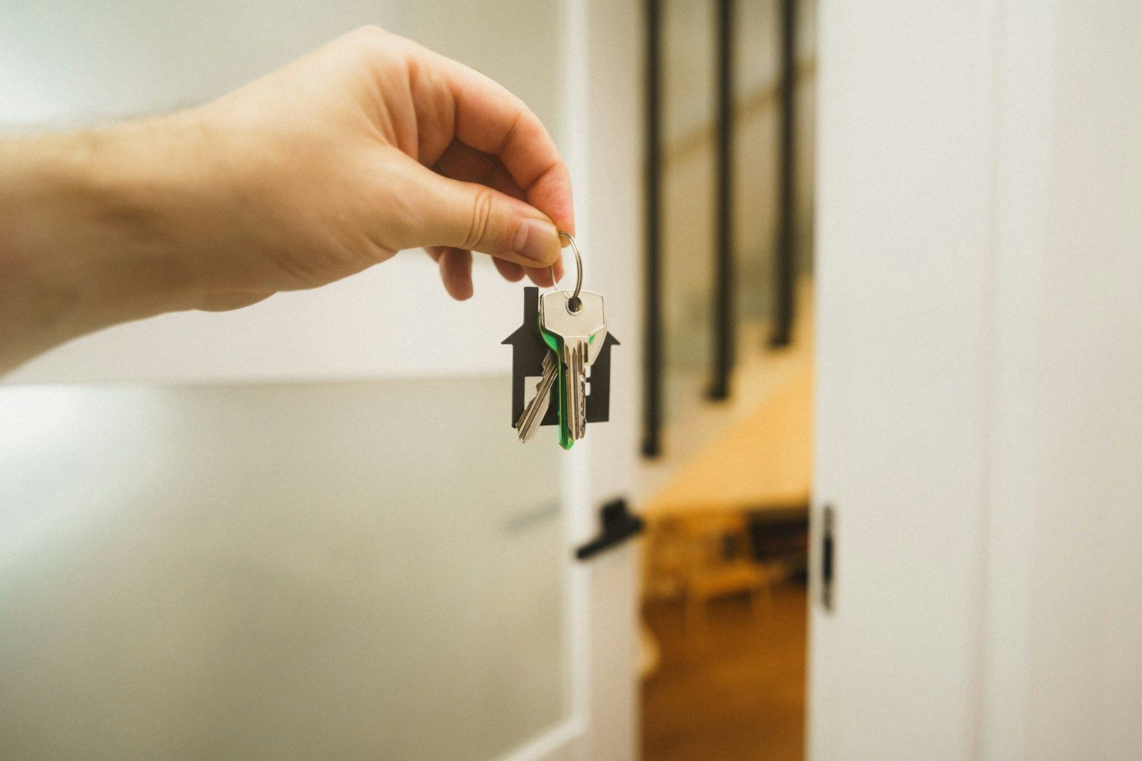 Hand holding a house key at a front door